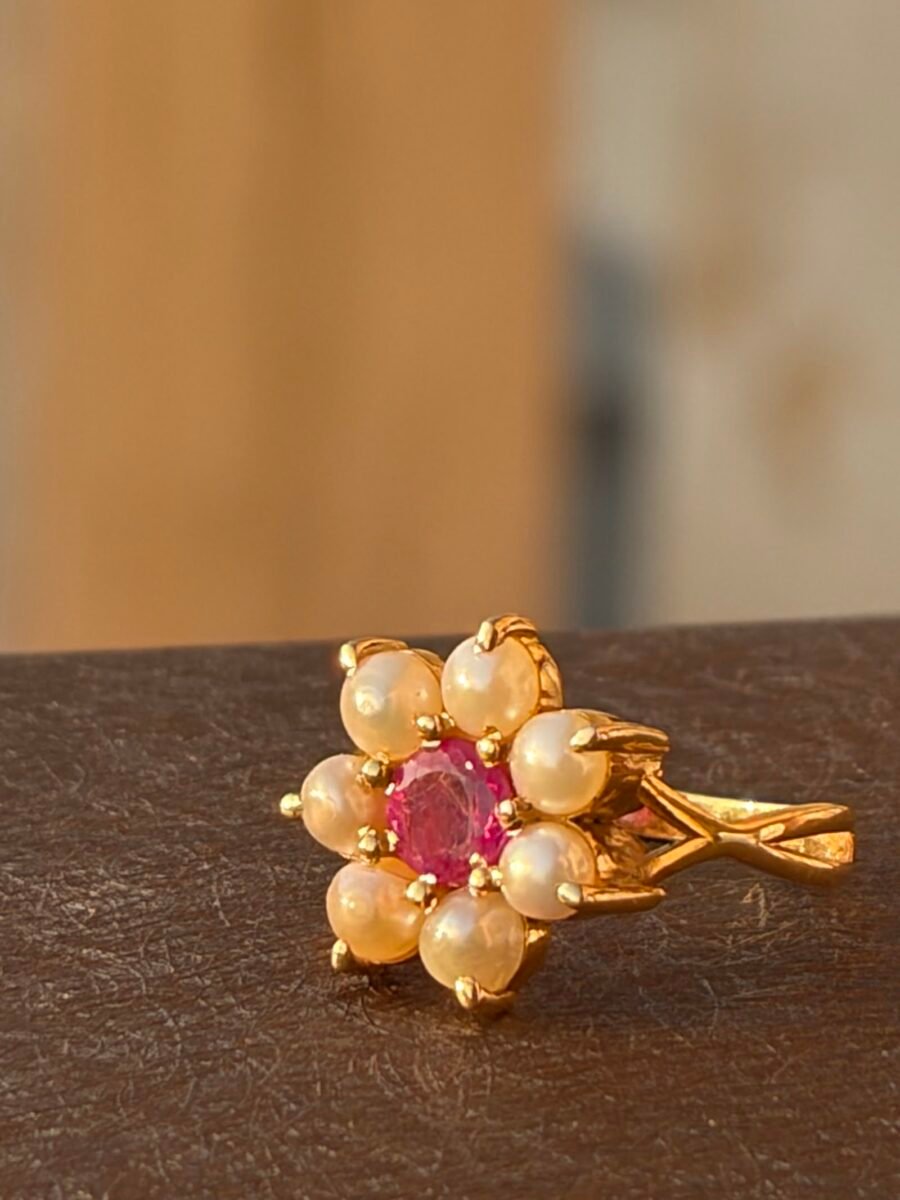 Gold ring with a ruby centre set in a flower of pearls