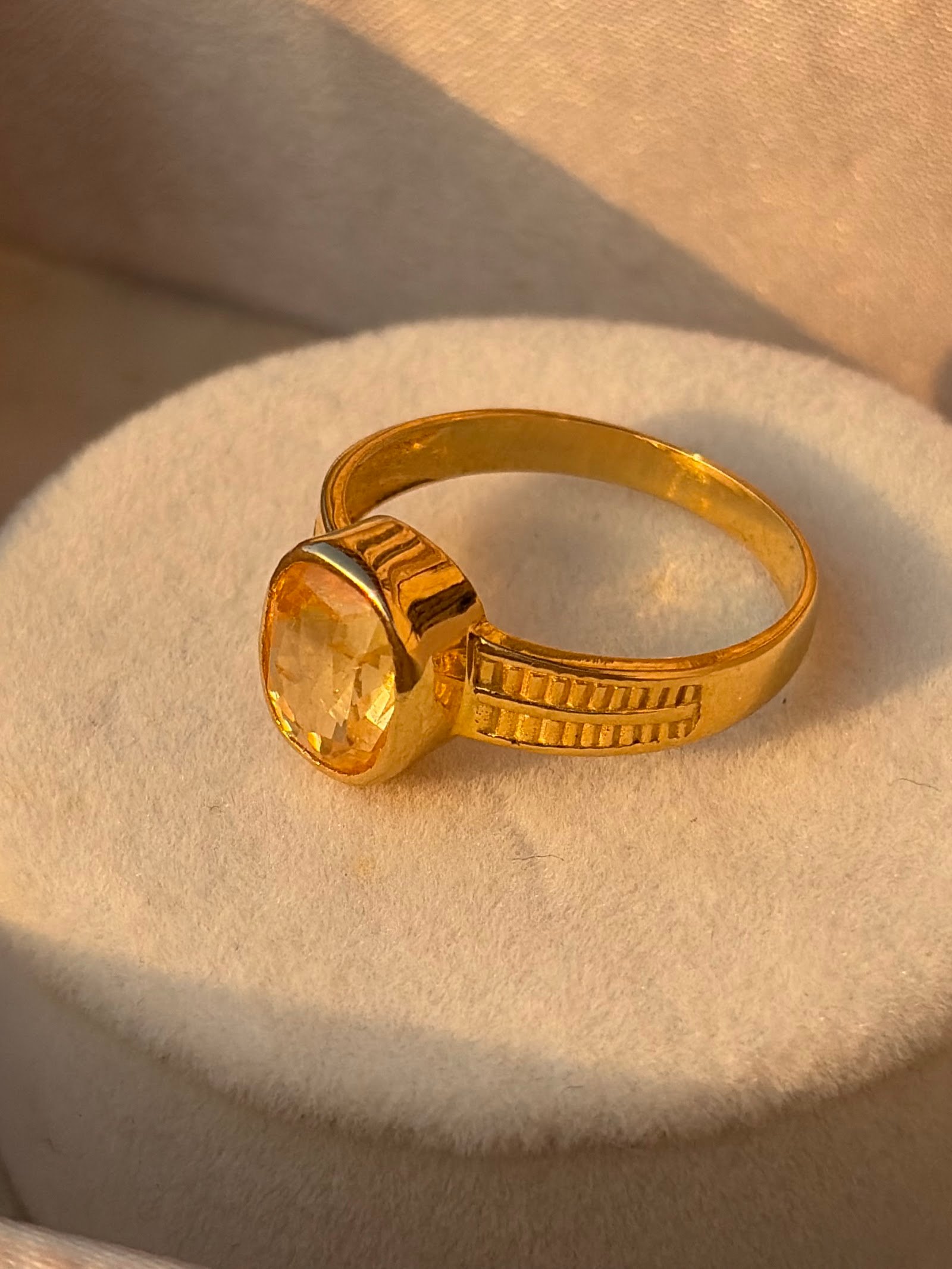 Gold ring with an oval yellow stone in a bezel setting