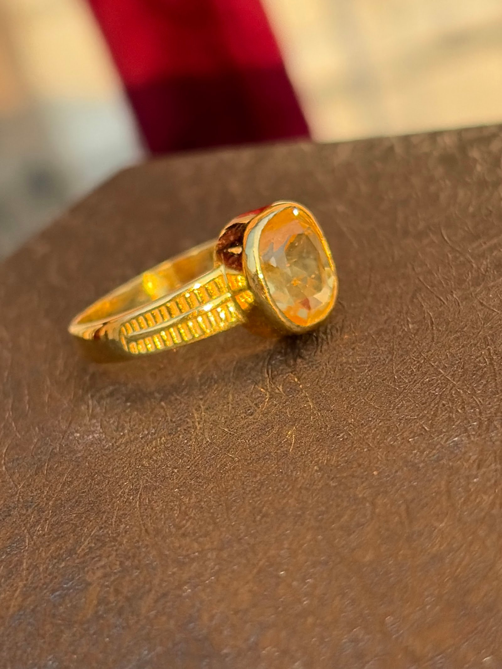 Gold ring with an oval yellow stone in a bezel setting